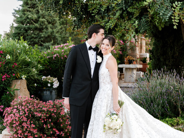 Newlyweds embracing beside flowering plants during their countryside wedding portraits