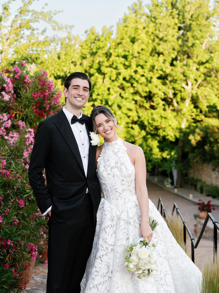 Bride and groom posing together beside flowering bougainvillea during golden-hour portraits
