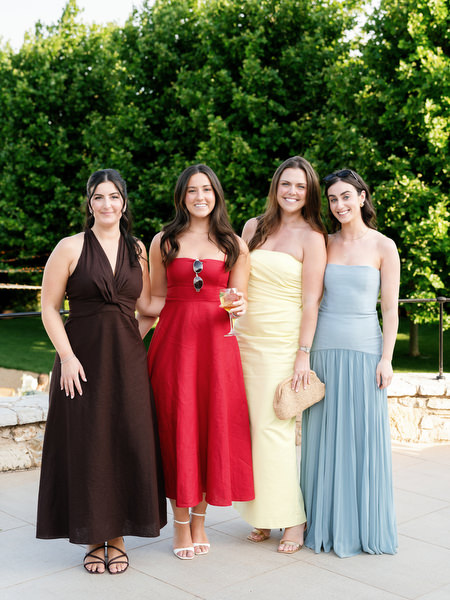 Four elegantly dressed women posing together during the Athens wedding reception