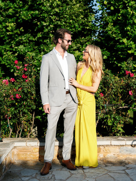 Wedding guest couple posing beside flowering bougainvillea at Pyrgos Petreza