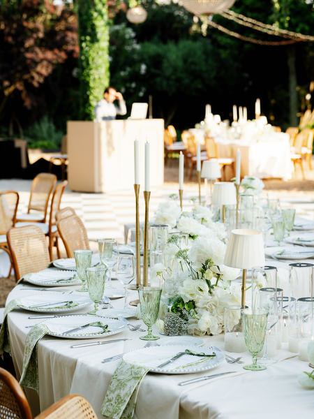 Elegant reception table styled with white florals, candles and glassware