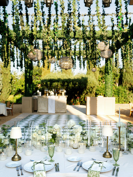 Wedding reception decor with hanging greenery and woven basket lights above the tables