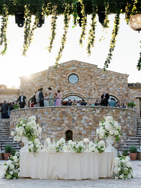 Sweetheart table framed by white flowers and the stone architecture of Pyrgos Petreza