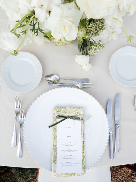 Elegant wedding place setting with menu, white plate and floral details