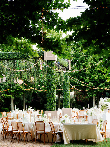 Outdoor dinner tables beneath lush greenery and hanging lights at Pyrgos Petreza