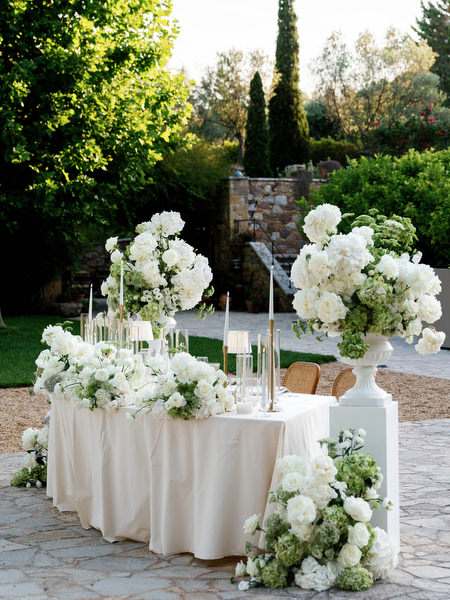 White floral arrangement and candlelit table details at the Athens wedding reception