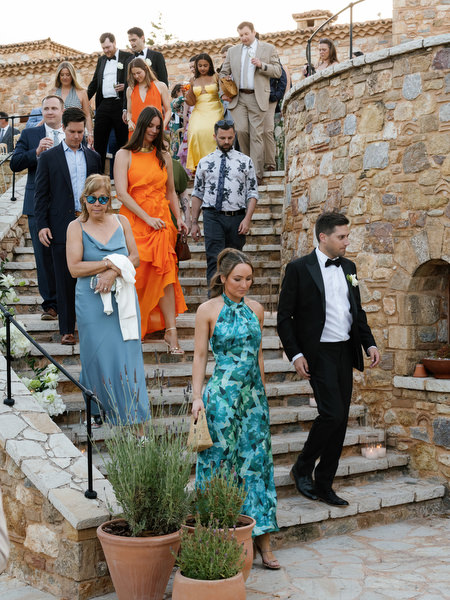 Wedding guests walking down the stone steps toward the Pyrgos Petreza reception