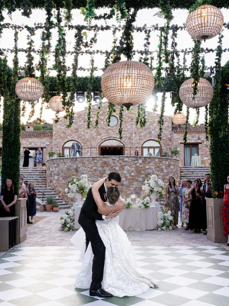 Bride and groom dancing as guests watch from around the patterned dance floor
