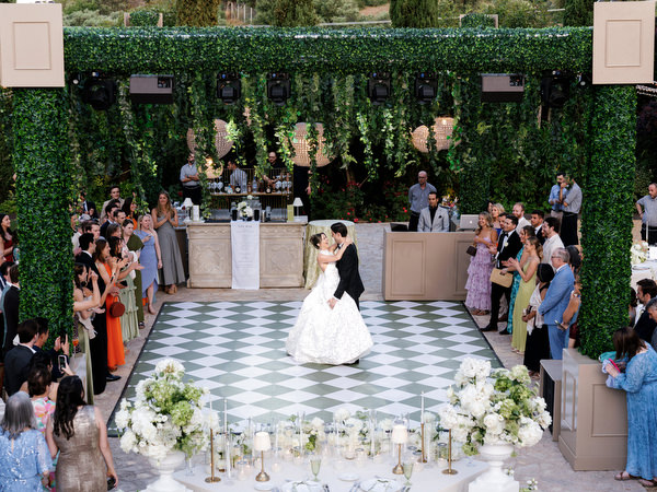 Wide view of the first dance beneath greenery and woven lights at Pyrgos Petreza