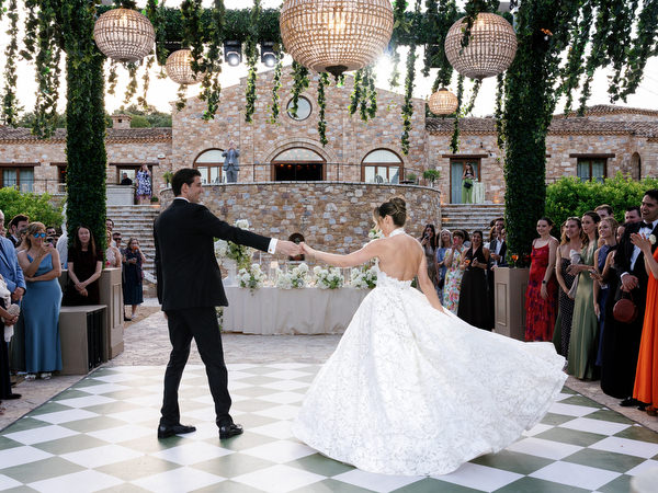 Groom twirling the bride across the patterned dance floor during their reception