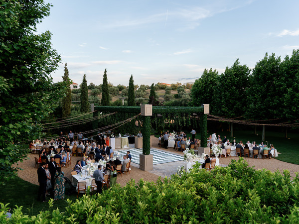 Outdoor wedding dinner under string lights with the countryside landscape beyond
