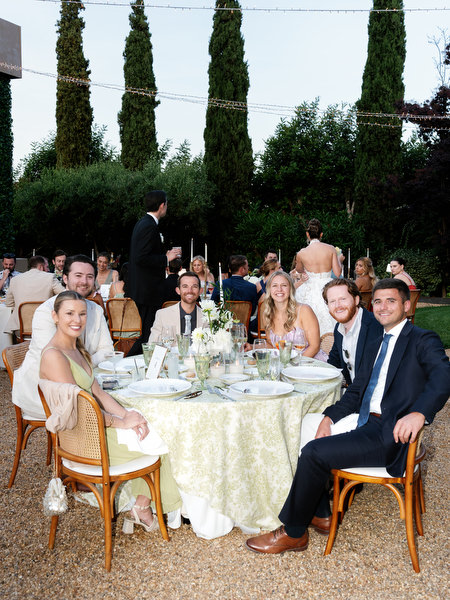 Guests seated at round dinner tables beneath the evening lights near Athens