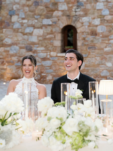 Bride and groom laughing together during speeches at their sweetheart table