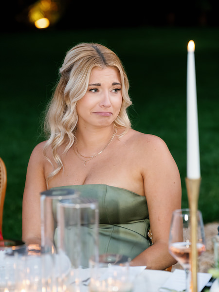 Wedding guest listening during dinner beside a tall candle at the reception