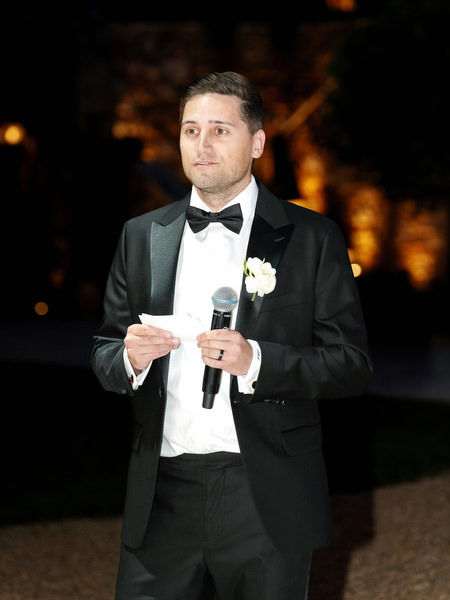 Groomsman holding a microphone during an emotional evening speech