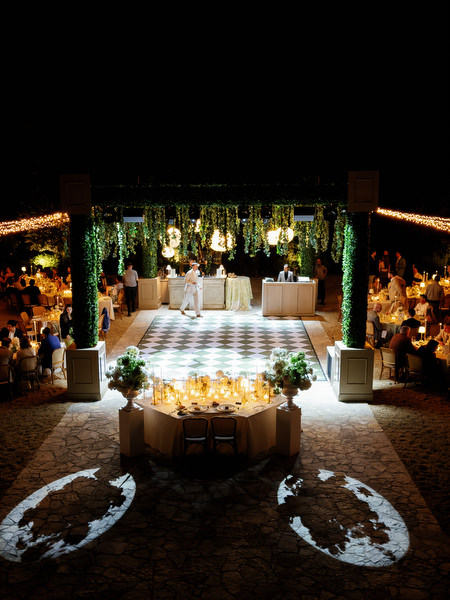 Nighttime reception scene with candlelight, greenery and hanging woven lights