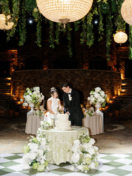 Bride and groom celebrating beside the wedding cake during the evening reception