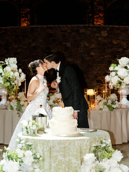 Bride and groom cutting their wedding cake beneath glowing reception lights at Pyrgos Petreza
