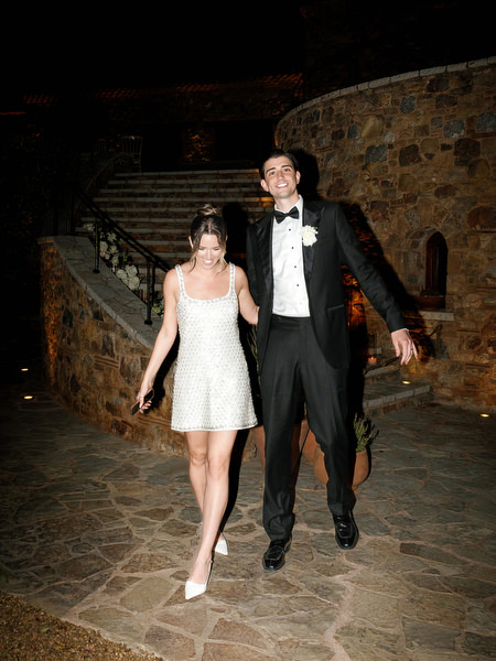 Bride and groom walking together through the stone venue during the evening