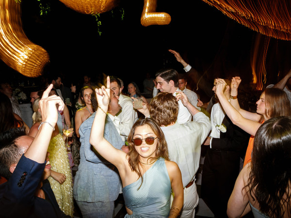 Guests raising their hands and dancing beneath woven lights at Pyrgos Petreza