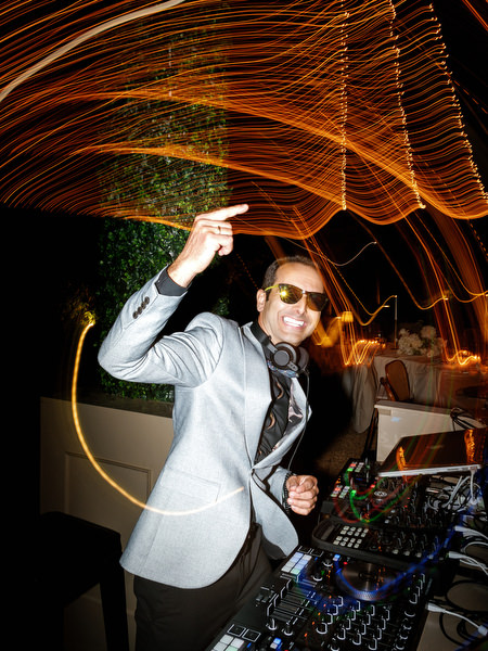DJ performing beneath warm string lights during the Pyrgos Petreza wedding party